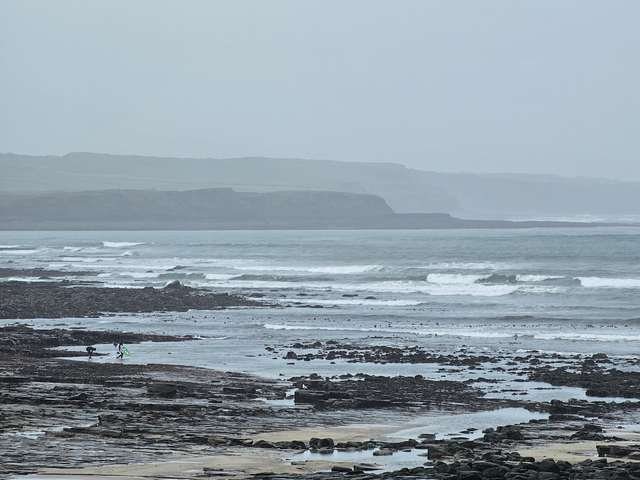 a pair of surfers getting ready to hit the water at Cornish point